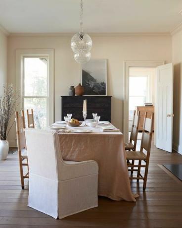 étkezőasztal, poros rózsaszín terítő, fa étkezőszékek, fehér anyagú végszékek, kandalló