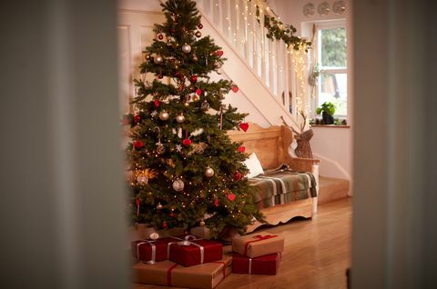 Fából készült karácsonyra díszített otthoni folyosó és ajándékok, a nyitott ajtón keresztül