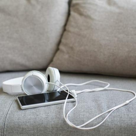 fülhallgató és okos telefon a kanapén