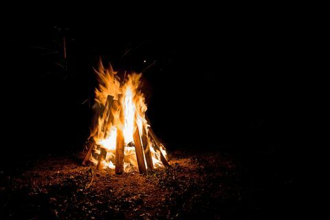 szabadtéri máglya magas lángokkal, teepee alakú táblákban