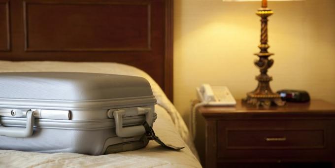 bőrönd az ágyon a szállodai szobában